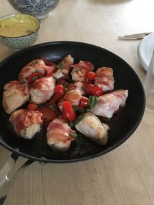 Pande med stegt kylling stykker om rullet med bacon, tomater og basilikum